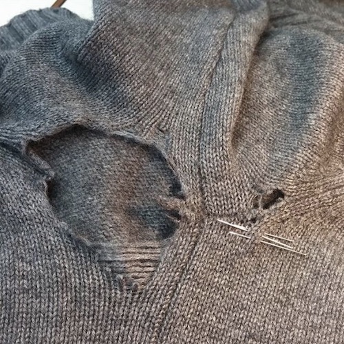 Beschädigte Strickkleidung vor dem Kunststopfen